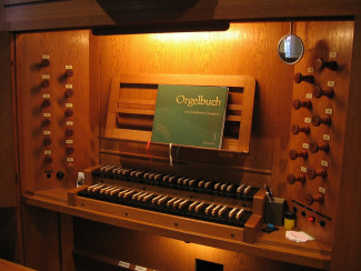 Ein Orgelmanual mit einem Notenheft auf dem Notenbrett